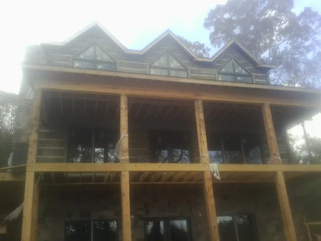 Dormers and porch framing on a large log home under construction — Roof Coating work by our crew in Peru